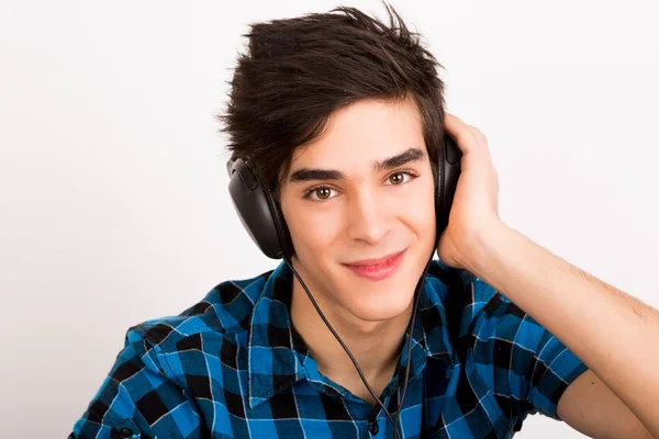 Nuori mies kuuntelee musiikkia kuulokkeet kotona — kuvapankkivalokuva