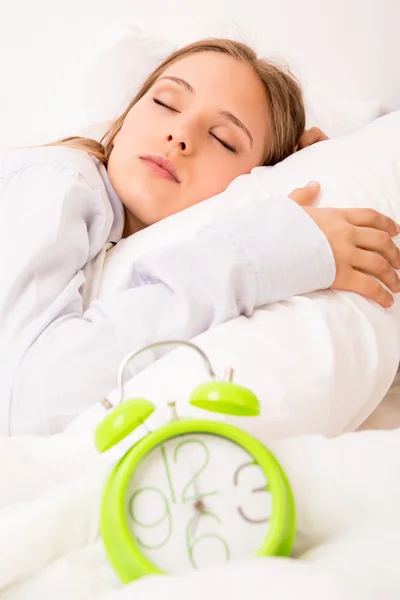 Krásná žena s alarmclock na postel — Stock fotografie