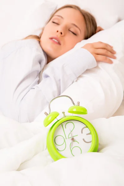 Schöne Frau schläft mit Wecker auf dem Bett — Stockfoto