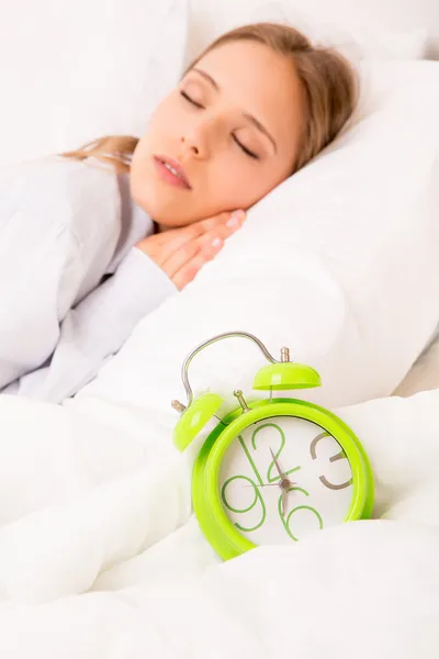 Schöne Frau schläft mit Wecker auf dem Bett — Stockfoto