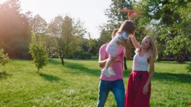 İki küçük çocuklu büyük bir aile parkta birlikte iyi vakit geçirir. Birlikte güler yüzlü, rahat hissederler.