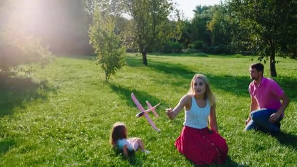 Los padres jóvenes disfrutan del momento con sus hijos en el medio del parque en la hierba jugando juntos muy divertido — Vídeos de Stock