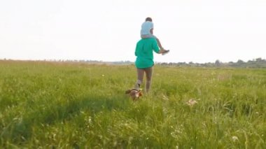 Oğluyla birlikte çimlerin üzerinde koşan bir adam onların peşinden koşan sevimli İngiliz cocker spaniel 'i taze havanın tadını çıkarın.