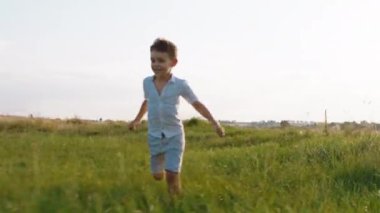 Geniş bir tarlanın ortasında, kameranın önünde çimlerin arasından hızla koşan, doğaya kocaman bir gülümsemesi olan karizmatik sevimli çocuk.