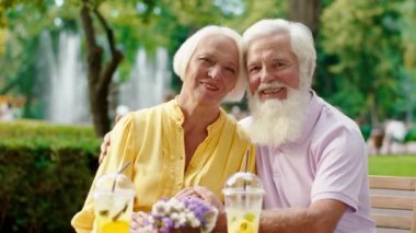 Kameranın önünde kameraya bakıp poz veren yaşlı ve güzel bir çiftin portresi var.