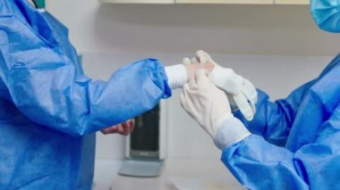 Kamera hemşiresi asistanına yakın koruyucu lateks eldivenleri al ve doktora onları giydirmesi için yardım et.