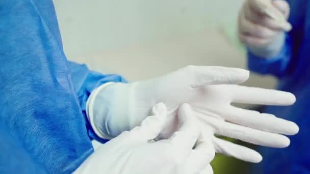 Близько до камери лікар бере захисні рукавички перед початком хірургічної операції — стокове відео