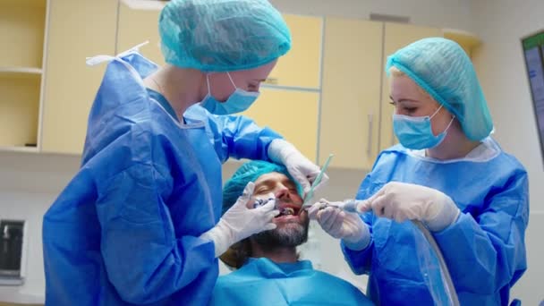 Modern dişçi kadın asistanının yardım ettiği oral tedaviye başlamadan önce hastasına anestezi yapıyor. — Stok video
