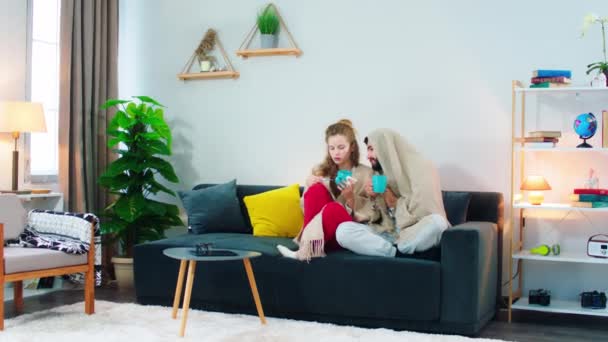 Ein Mann und eine Frau sitzen auf einem Sofa und überprüfen ihre Temperatur und schnuppern an ihren Nasen, während sie aussehen, als hätten sie eine Erkältung — Stockvideo