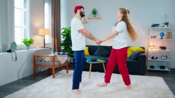 Härligt ungt par man och kvinna i vardagsrummet dansar romantiskt tillsammans och känner avslappnad din fortkörning en bra tid tillsammans hemma — Stockvideo