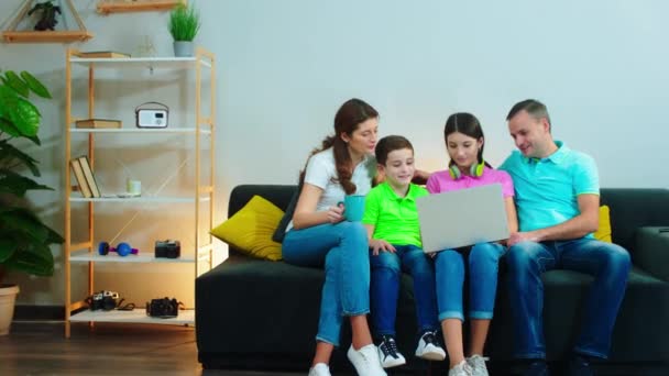 Große charismatische Familie verbringt eine gute Zeit zusammen zu Hause auf dem Sofa und schaut zusammen einen Film auf dem Laptop — Stockvideo
