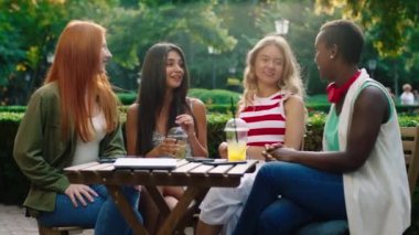 Çok heyecanlı bir grup güzel bayan siyahi kadın ve çok ırklı arkadaşlar parkın ortasındaki kafede dostça sohbet ediyorlar. 4k