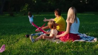 Güneşli bir günde, parkta çocuklarla oynayan ve birlikte vakit geçirmek için çimenlere uzanan büyük bir aile. ARRI Alexa Mini 'de çekilen.