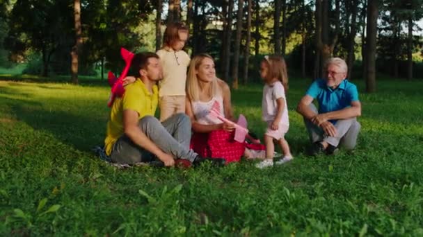 En medio del parque en un día soleado familia feliz y dos niños lindos y carismáticos jugando juntos conversación y sonriendo a lo grande. 4k — Vídeos de Stock