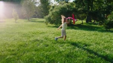 Güneşli bir günde parkta güzel bir çocuk büyük kırmızı bir uçakla konsantre ve hevesli oynuyor. 4k