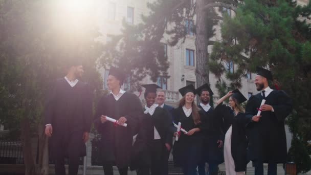 Día de graduación grupo de estudiantes graduados multirraciales en el grupo caminando junto con el director de la universidad delante de la cámara que sonríen gran sensación emocionada vomitar la graduación — Vídeos de Stock