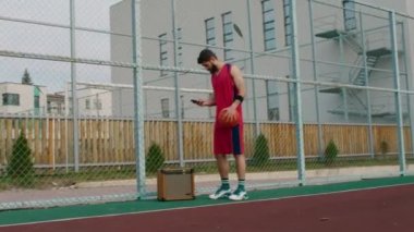 Basketbol sahasındaki kırmızı takım elbiseli genç adam maça hazır ol. Hoparlörüne biraz müzik koydu ve topla oynamaya başladı.