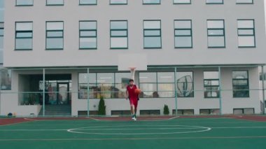 Modern büyük basketbol sahasında kameranın önünde basketbol oynayan yakışıklı adam topun peşinden koşuyordu.
