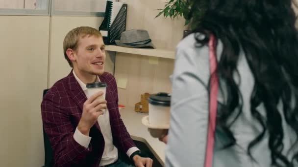 Харизматичный офисный менеджер мило беседует со своей помощницей в офисе, пока она приносит ему кофе на вынос — стоковое видео