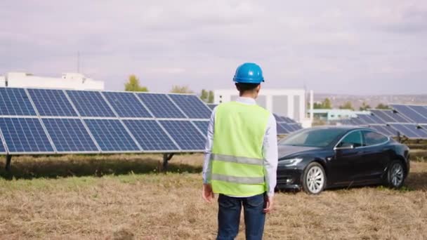 Paneles solares granja caminando energía a través de las baterías fotovoltaicas a su coche ecológico que llevaba casco de seguridad concepto de energía verde futura energía renovable. Disparo en ARRI Alexa Mini. — Vídeo de stock