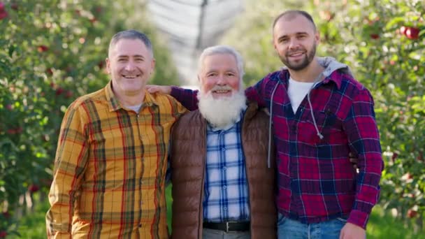 Lachende grote oude man boer en zijn zonen voor de camera poseren opgewonden nadat hij einde te halen alle rijpe appels van de boomgaard — Stockvideo