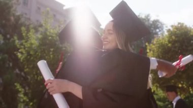 İyi görünümlü çok ırklı arkadaşlar mezuniyetten sonra her birini tebrik ettiler diplomalarını tuttukları ve heyecanlandıkları için mutlu oldular. 4k