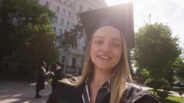 Selfie video rejestrując jedną absolwentkę mówi coś dla swoich rodziców po ukończeniu studiów trzyma dyplom w rękach — Wideo stockowe