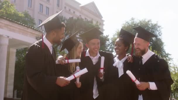 Ótimo olhar jovens estudantes graduados abraçando em grupo todos juntos discutindo e se sentindo animado na frente da câmera no jardim da faculdade. Tiro em ARRI Alexa Mini. — Vídeo de Stock