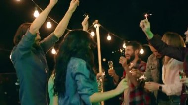 Bir grup çok ırklı insan terasın tepesinde parti veriyor. Dans ediyorlar ve gecenin tadını çıkarıyorlar. Biraz pırıltı tutup şampanya içiyorlar.