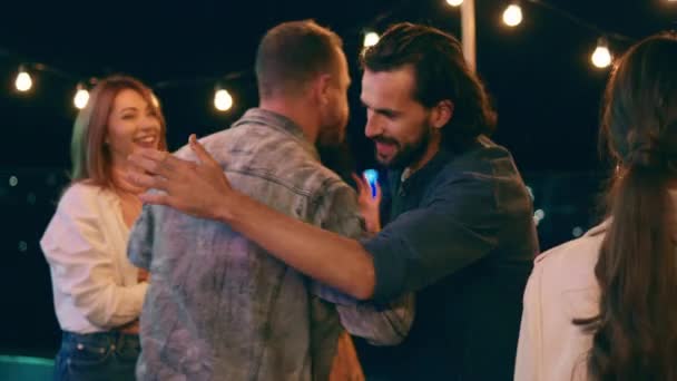 Pria tampan datang ke pesta katanya dia kepada semua orang dan memeluk teman-temannya di atap teras — Stok Video
