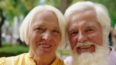 Kameranın önünde birbirine aşık sevimli yaşlı bir çift. Kocaman gülümseyen ve düz bir portre çeken.