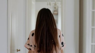 Güzel pijama şortlu ve kollarını havaya kaldırmış bir kadın başka bir odaya doğru yürüyordu.
