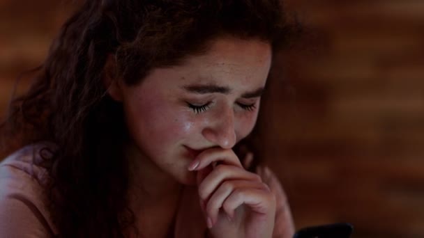 Fechar-se para a câmera menina deprimida chorando em seu quarto ela segurando um smartphone nas mãos — Vídeo de Stock