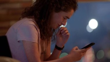 Oturma odasında ağlayan kadın, kanepede otururken laptopunda bir şey arıyor ve aynı anda elinde akıllı telefon tutuyor.