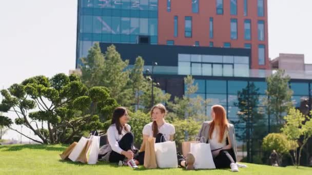 Good looking ladies have a great day after shopping excited chilling on the park down on the park discussing and enjoy the sun — Stock Video