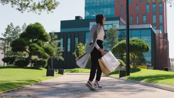 昼食の後、オフィスワーカーの女性が戻ってきて、彼女はメインのビジネスセンターに歩いていくつかのエコショッピングバッグを持っています — ストック動画