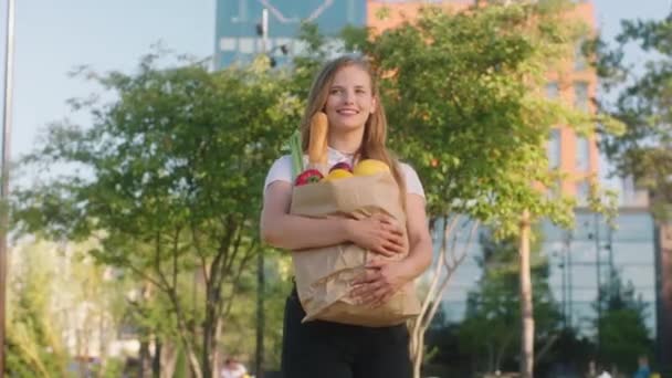 Fantastisk kvinna med ett stort leende går ner på gatan med en stor eko väska full av grönsaker och frukter — Stockvideo