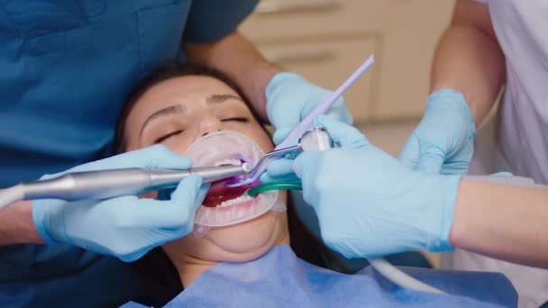 In maschera protettiva bello dentista uomo e il suo assistente curare i denti del paziente che lavorano concentrati insieme. 4k — Video Stock