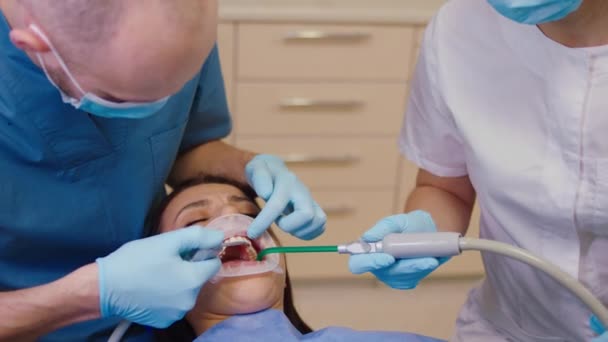현대의 치과 의사와 그 의보 조자인 암컷 이여성 환자에게 구강 치료를 받고 있다 — 비디오