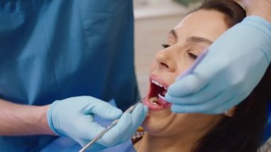 Diş sağlığı kliniğinde dişçiye gidip dişlerini kontrol eden güzel bir kadın var.