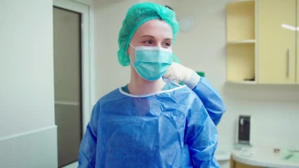 Enfermeira fêmea ajudando a vestir a mulher médica com o uniforme especial para iniciar uma operação cirúrgica — Vídeo de Stock