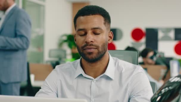 Um homem negro carismático com uma leve barba, está usando um botão azul no trabalho e cruzando seus braços sorrindo amplamente — Vídeo de Stock