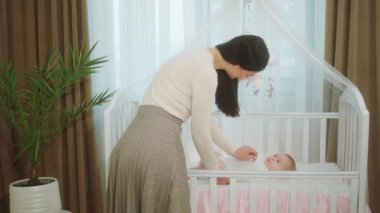 Bebek karyolasına uzanmış bebeğiyle sürat yapan annelik ve çocukluk kavramı. Bebeğe çok dikkatli bir şekilde dokunuyor.
