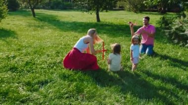 Mutlu genç ebeveynler ve çocukları parkın ortasında birlikte iyi vakit geçiriyorlar ve birlikte vakit geçiriyorlar.