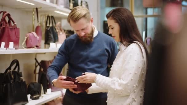 I en liten accessoar butik karismatisk man försöka välja en present till sin fru försäljaren hjälper glad kunden att välja rätt present. Skjuten på ARRI Alexa Mini. — Stockvideo