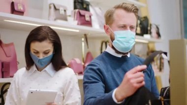 Coronavirus salgınında iki mağaza işçisi kadın denetçi dijital tablet kullanarak fiyat değişikliği yaparken diğer işçiler mağazalardaki yeni ürünleri kontrol ediyor.