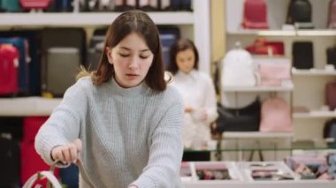 Mutlu ve karizmatik satıcı, güzel bayan müşteriye aksesuar dükkanından bir çanta seçmesi için yardım etmeye çalışır.