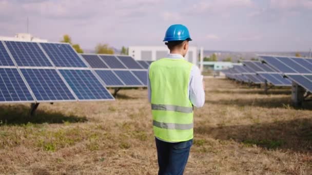 Průmyslový mechanik procházející parkem solárních panelů pomocí digitálního tabletu shromažďuje efektivní informace o fotovoltaických solárních bateriích — Stock video