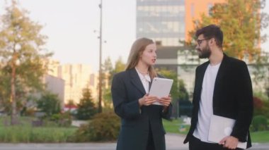 Modern iş parkındaki iş konsepti. İki ofis çalışanı kadın ve adam tablet kullanarak bazı görevleri tartışıyor. Gülümsüyorlar ve rahatlıyorlar.