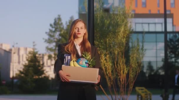 完璧な晴れた日に動揺した女性のオフィスマネージャーは、彼女が彼女のオフィスのものを保持する通りを歩く仕事から解雇されましたボックスの背景に大きなビジネスセンタービル。Arri Alexa Mini. — ストック動画